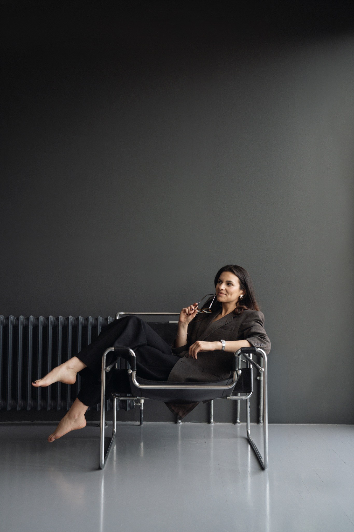 Ola seated in a modern chair against a dark grey studio backdrop